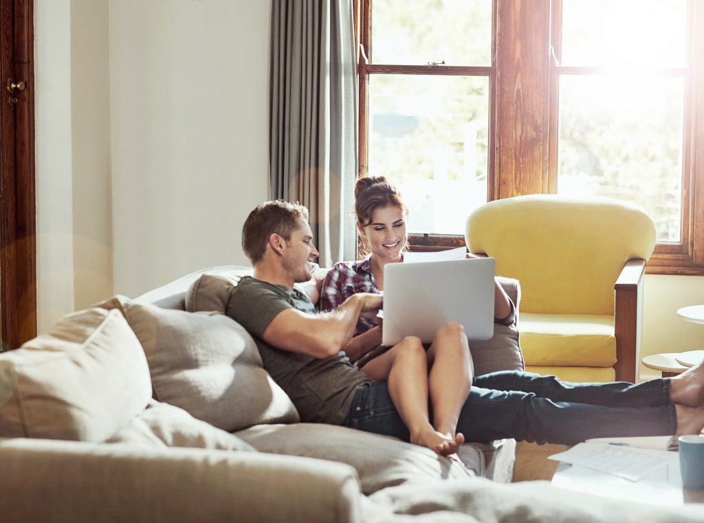 Young couple using laptop on sofa