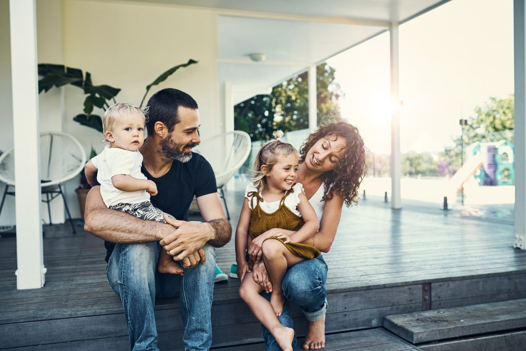 Young happy family sitting on front porch of home