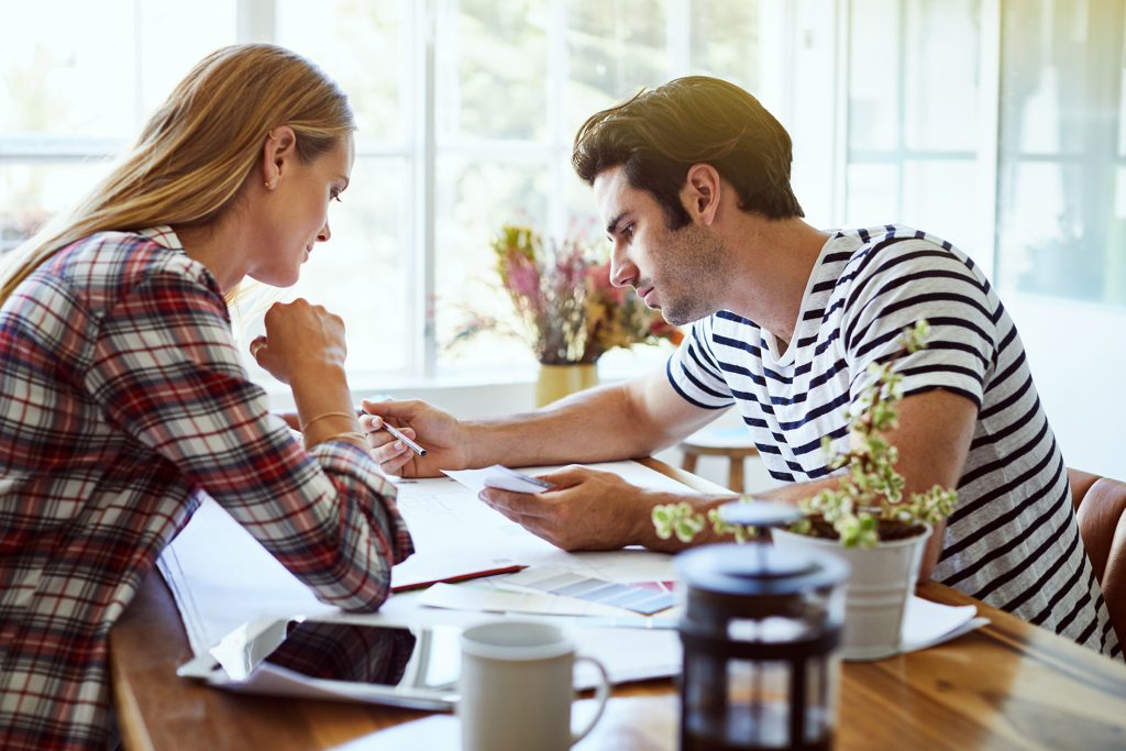 Young couple looking over budget at kitchen table