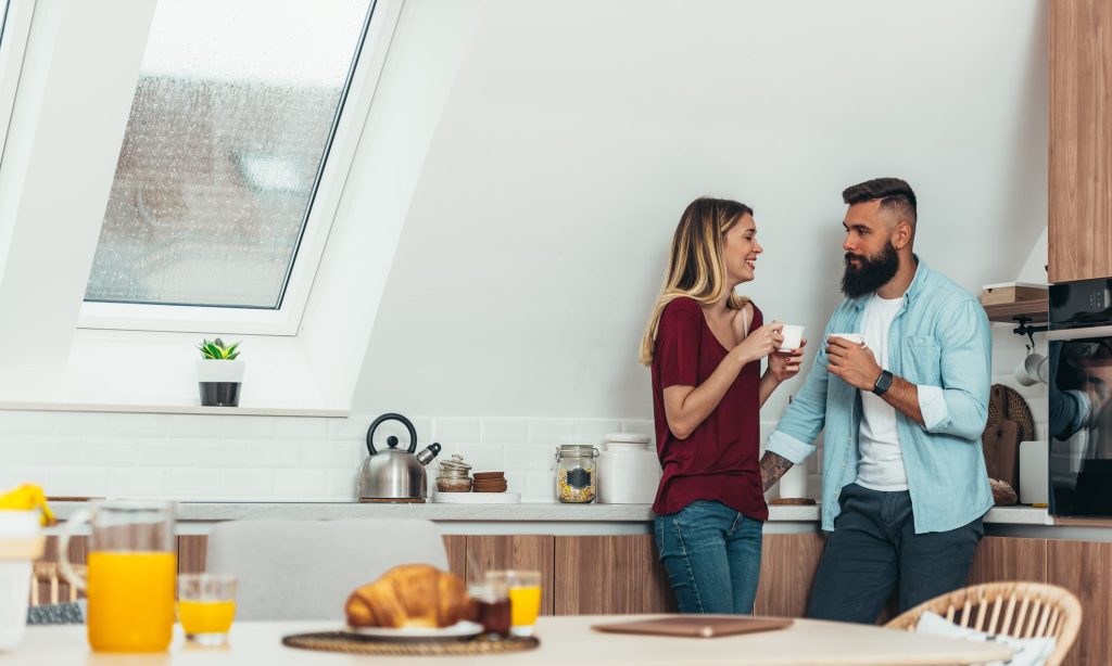 Young couple drinking coffee in the kitchen at home
