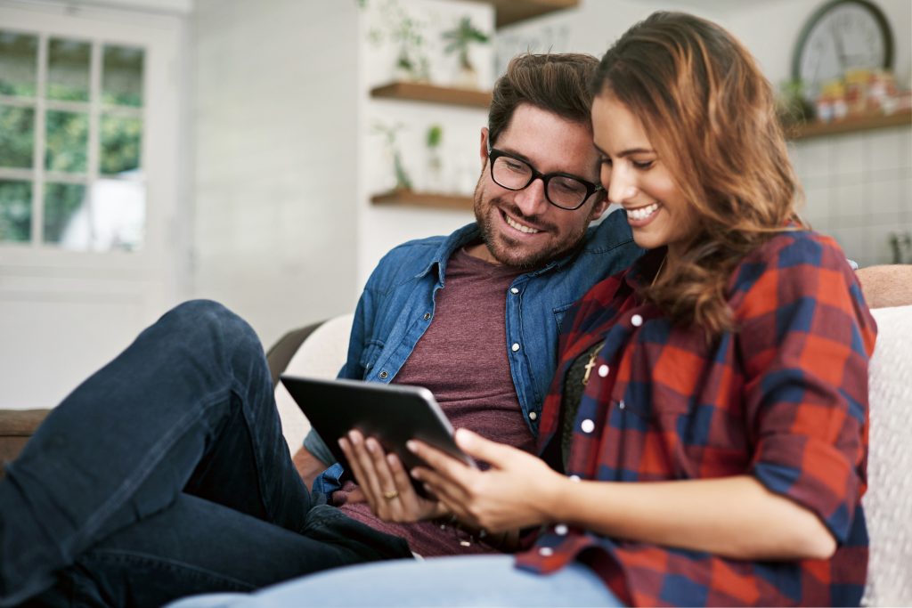 couple using a tablet together on the sofa at home